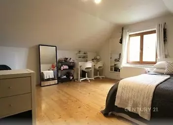 Prostorná ložnice s dřevěnou podlahou, velkým oknem a moderním nábytkem, nabízí světlý a útulný interiér ideální pro pohodlné bydlení.