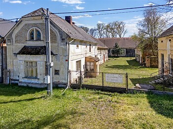 Průmyslový areál s rekonstruovanými budovami, velkým dvorem a oplocením, ideální pro komerční využití a rozvoj podnikání.