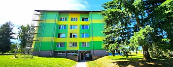 Zrekonstruovaný panelový dům s barevnou fasádou v klidné lokalitě obklopený zelení, nabízí prostorné bytové jednotky s moderními prvky.