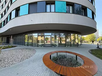 Moderní komerční prostor s velkými okny, moderní architekturou a dlažbou na terase, ideální pro podnikání v dynamické lokalitě.