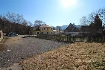 Prostorný zahradní pozemek s výhledem na okolní krajinu, obklopený venkovskými domy. Klidné prostředí, vhodné pro rodinné bydlení.