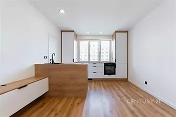 Moderní kuchyň s parketovou podlahou, velká okna poskytující dostatek světla, vestavěné skříně a minimalistický design