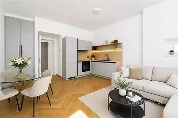 Světlý obývací pokoj s moderní kuchyní, parketová podlaha, velká okna, elegantní nábytek, světlý design, útulná atmosféra.