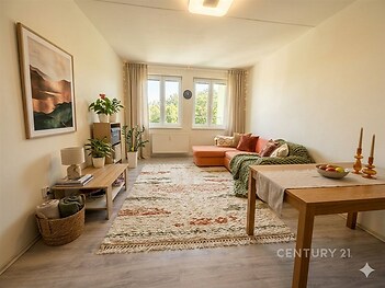 Světlý obývací pokoj, moderní laminátová podlaha, velká okna, útulný styl, vestavěné dekorace, prostorný interiér.