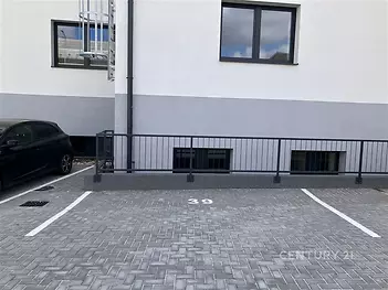 Prázdné parkovací místo s dlažbou, označené číslem 39, vedle moderní budovy. Vhodné pro parkování rezidentů v městské oblasti.