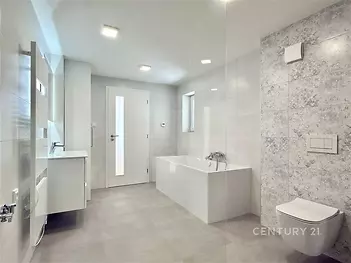 Prostorná koupelna s moderní dlažbou, velkou vanou a závěsnou toaletou, světlé provedení a elegantní povrchové úpravy Созданоieun