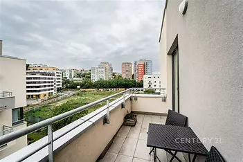 Moderní balkon s dlažbou a výhledem na městskou zástavbu, vybavený elegantním zahradním nábytkem, ideální pro relaxaci