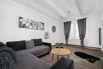 Světlý obývací pokoj s moderním designem, parketová podlaha, velká okna s elegantními závěsy, kvalitní nábytek, rekonstruovaný interiér.