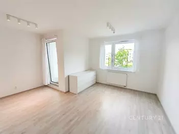Světlý obývací pokoj s parketovou podlahou, velkými okny a moderním osvětlením nabízí pohodlný a svěží prostor k relaxaci.