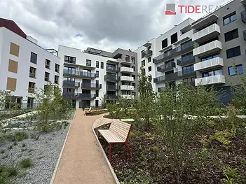 Moderní bytový komplex s balkony, upravenou zahradou a pěšími cestami, nabízí moderní styl a klidné prostředí pro bydlení.