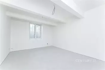 Prázdná místnost s bílými stěnami, betonová podlaha, velké okno, moderní rekonstrukce, minimalistický design.