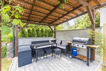 Zahradní terasa s pergolou, moderní dlažbou a zahradním nábytkem, ideální pro relaxaci a grilování, součástí je i plynový gril