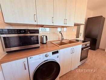 Kompaktní kuchyň s dřevěnou linkou, vestavěné spotřebiče, dlažba na podlaze, moderní provedení vhodné pro efektivní využití prostoru.