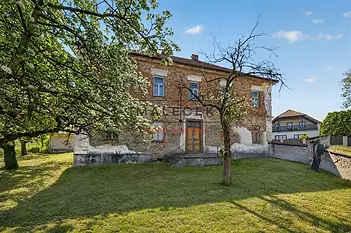 Historická budova s cihlovou fasádou, velkou zahradou a šikmou střechou, nabízí potenciál pro renovaci v klidné lokalitě.