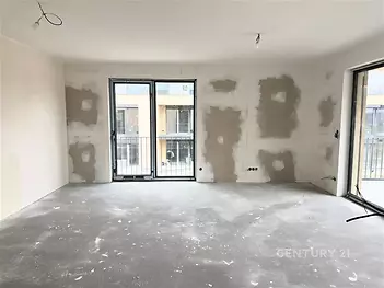 Prázdný obývací pokoj s balkonovými dveřmi, betonovou podlahou a přípravou na osvětlení, připravený k finalizaci v moderním stylu