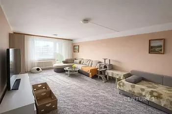 Prostorný obývací pokoj se světlým koberce, velkými okny a útulným nábytkem, nabízí světlý interiér s moderním designem.