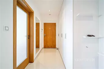 Světlá předsíň s dlažbou, moderní vestavěné skříně a dřevěné dveře, minimalistický design a čisté linie pro elegantní vzhled.