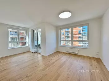 Světlý obývací pokoj s parketovou podlahou, velká okna, moderní úpravy, výhled do ulice, ideální prosluněný interiér.