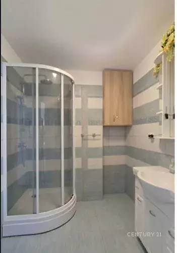 Koupelna s moderní sprchovým koutem, dlažba ve světlých odstínech, vestavěná skříňka, světlý interiér.
