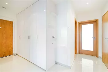 Vstupní hala s vestavěnými skříněmi, bílými stěnami a dřevěnými dveřmi, dlažba na podlaze, moderní a světlý styl.