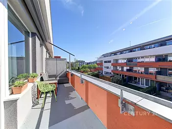 Prostorný balkón s moderní dlažbou, výhled na okolní budovy a zahrady, ideální pro relaxaci na svěžím vzduchu.