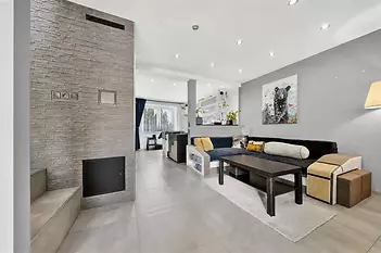 Světlý obývací pokoj s moderní dlažbou, krbovými kamny a velkými okny, které zajišťují dostatek přirozeného světla, v moderním stylu.