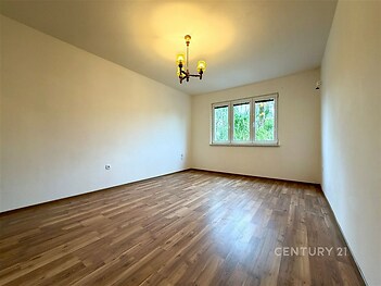 Prostorný obývací pokoj, parketová podlaha, velká okna, moderní styl, světlé prostředí, ideální pro rodinné bydlení.