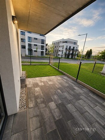 Terasa s moderní dlažbou nabízí ideální místo k relaxaci, s výhledem na okolní architektonicky střízlivé budovy a upravený trávník.