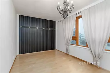 Ložnice s parketovou podlahou, velká okna, elegantní lustr, moderní interiér, světlý prostor, minimalistické dekorace.