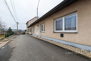 Fasáda rodinného domu s moderními okny na klidné ulici nabízí pěkný výhled na okolní krajinu. Výborný stav a upravené okolí.