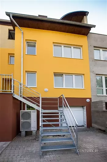 Fasáda rodinného domu s barevným nátěrem, moderní plastová okna, kovové venkovní schodiště, nedávno rekonstruovaný exteriér.