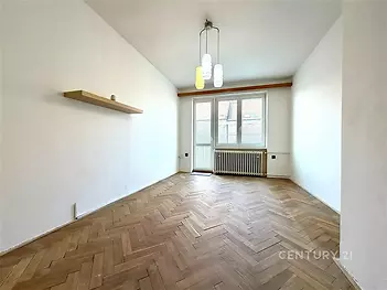 Světlý obývací pokoj s parketovou podlahou, velká okna, moderní lustr, prostor pro vestavěné skříně, příjemná atmosféra.