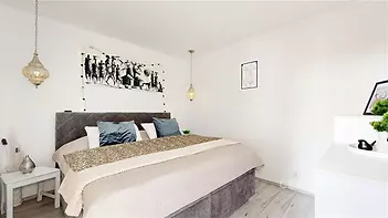 Prostorná ložnice s moderní dekorací, laminátová podlaha, závěsné osvětlení, světlé stěny, elegantní atmosféra.