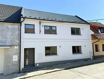 Fasáda moderního rodinného domu s novou střechou a plastovými okny se nachází v klidné ulici. Dům je po kompletní rekonstrukci.