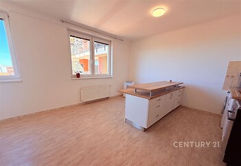Světlá kuchyň s parketovou podlahou, moderní kuchyňský ostrůvek a velká okna pro přirozené osvětlení.