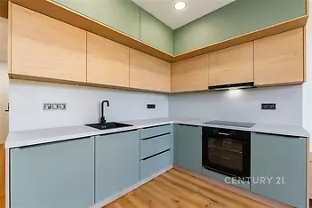 Moderní kuchyň s parketovou podlahou, vestavěnými skříněmi a elegantním designem. Kombinace dřeva a pastelových odstínů vytváří světlý prostor.