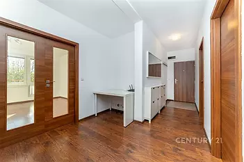 Prostorná chodba s parketovou podlahou, moderní nástěnnou skříní a dřevěnými dveřmi, poskytuje elegantní vstup do rekonstruovaného bytu.