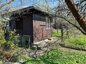 Malá zahradní chatka ze dřeva, situovaná v klidné zahradě, nabízí základní útočiště s možností úpravy a využití pro rekreační účely.