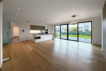 Prostorný obývací pokoj s moderní kuchyní, parketová podlaha, velká okna s výhledem do zahrady, světlý interiér.
