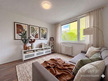 Světlý obývací pokoj s dřevěnou podlahou, velkým oknem a moderním designem, nabízí prostor pro relaxaci a prosvětlenou atmosféru.