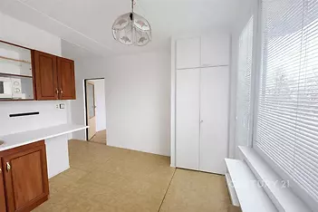 Světlá kuchyň s parketovou podlahou a vestavěnými skříněmi, doplněná velkými okny pro přirozené světlo, v moderním stylu.