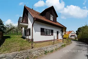 Rodinný dům s dřevěnými prvky, šikmou střechou a zahradou na klidném místě, ideální pro rekonstrukci a úpravy.