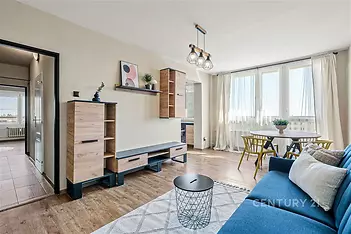 Světlý obývací pokoj s parketovou podlahou, velkými okny a moderním nábytkem. Světlé a vzdušné provedení ideální pro relaxaci.