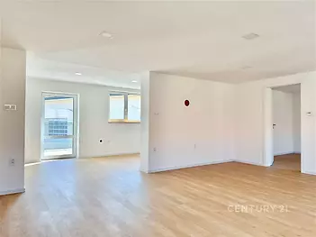 Prostorný obývací pokoj s parketovou podlahou, velkými okny a moderním designem, který nabízí světlý a vzdušný prostor pro bydlení.