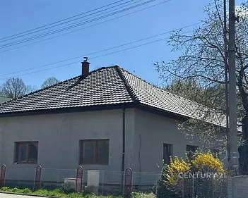 Rodinný dům s moderní střešní krytinou, obklopený zahradou, výrazná okna, tradiční venkovský styl, v klidné lokalitě.