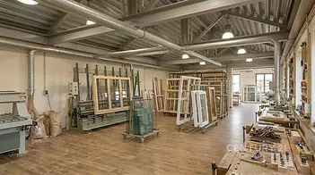 Prostorná dílna se světlým interiérem, parketovou podlahou a velkými okny, vybavená moderními zařízeními a pracovními stoly