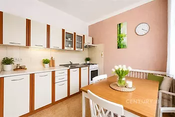 Moderní kuchyň s dlažbou, vestavěnými skříněmi a světlým jídelním koutem, ideální pro rodinné posezení.