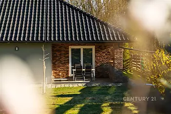 Exteriér domu s terasou, cihlovým obkladem a velkými okny, moderní styl. Udržovaná zahrada dodává příjemnou atmosféru.