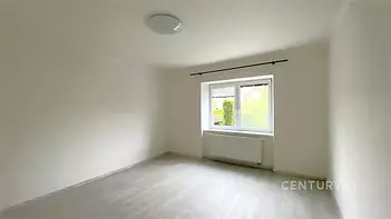 Světlá ložnice s moderními plastovými okny, světlou laminátovou podlahou a bílými stěnami, ideální pro přizpůsobení osobnímu stylu.