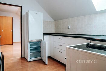 Moderní kuchyň s parketovou podlahou, vestavěné spotřebiče a světlá kachlová dlažba, podkrovní prostor s přirozeným osvětlením.